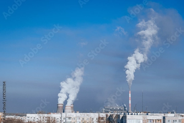 Obraz combined heat and power (CHP) system with industrial chimneys and white smoke on bright blue sky background