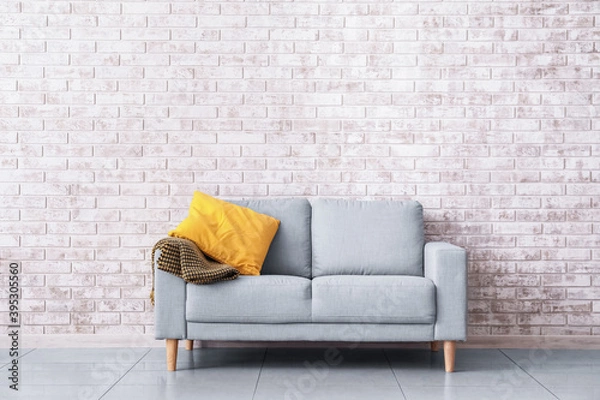 Fototapeta Stylish sofa near brick wall in room