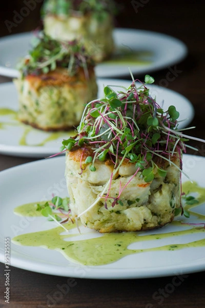 Fototapeta Crab cake. Crab served with spicy rémoulade sauce on top of a mixed green salad. Jumbo crab meat mixed with garlic, onions, spices & fried in butter. Classic American restaurant appetizer.