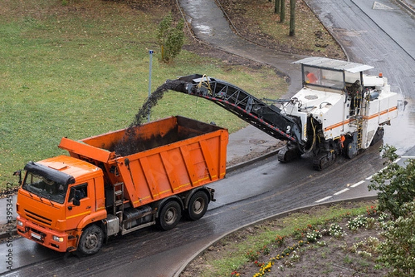 Obraz Road milling machine removes old asphalt and loads milled asphalt into the dump truck. Road construction working. Road repair process. Stock photo