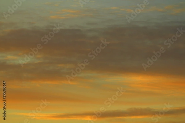 Fototapeta Sun below the horizon and clouds in the fiery dramatic orange sky at sunset or dawn backlit by the sun. Place for text and design