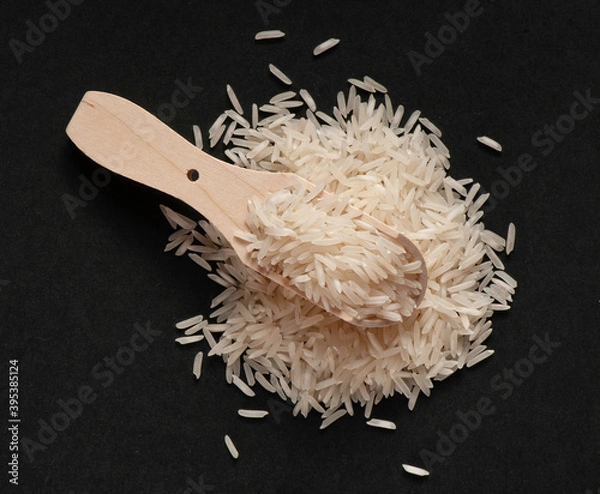 Fototapeta Heap of wite basmati rice with wooden scoop on black background.  Flat lay.