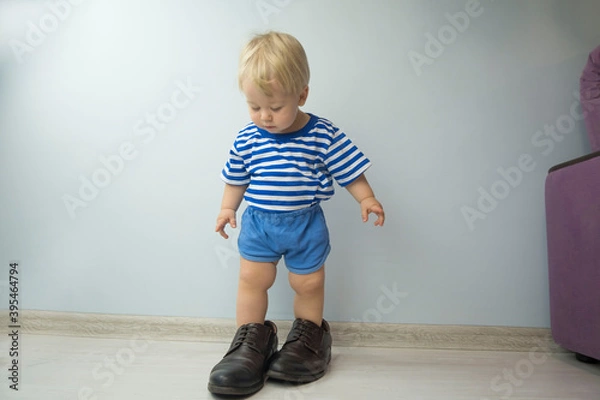Fototapeta small child, dressed in brown shoes large adult. the child wore dad's shoes