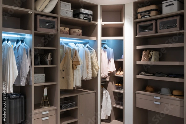 Fototapeta modern wooden wardrobe with clothes hanging on rail in walk in closet design interior