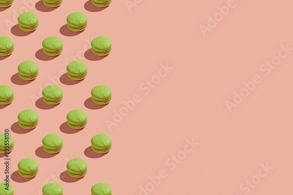 Obraz Green macaroons with shadows on colored background. Trendy minimal pattern with copy space. French cookies macarons on a pink pastel background. Delicious  french dessert. Creative modern background
