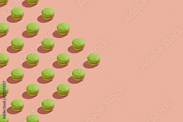 Obraz Green macaroons with shadows on colored background. Trendy minimal pattern with copy space. French cookies macarons on a pink pastel background. Delicious french dessert. Creative modern background