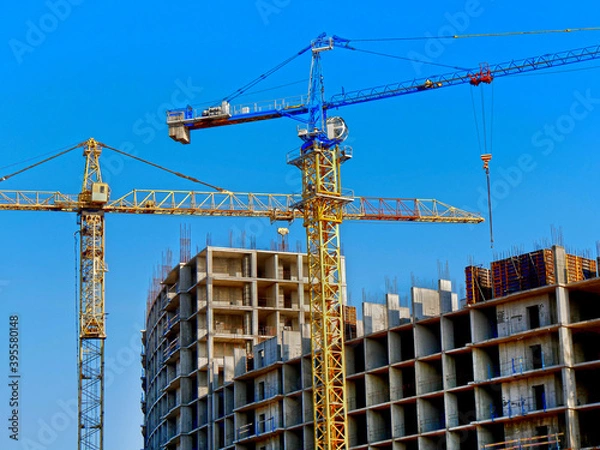 Obraz Two cranes near building. Concrete building under construction.