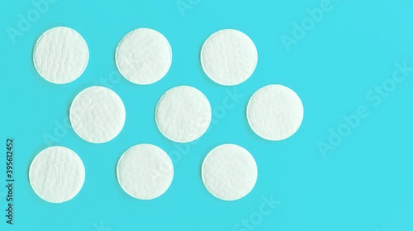 Fototapeta Nine white cotton cosmetic pads arranged on cyan blue board, closeup view from above