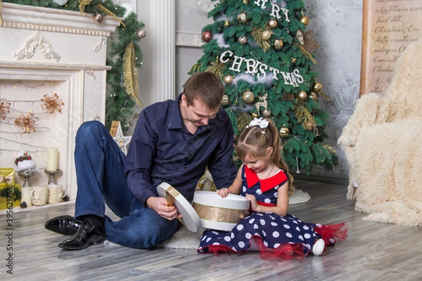 Obraz Surprised little daughter opening a Christmas present with her father at home