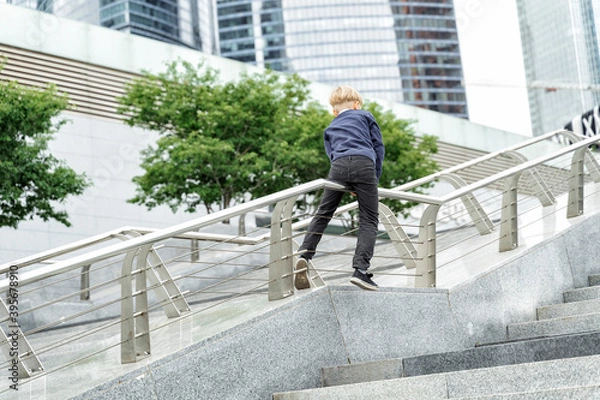 Fototapeta mischievous boy slides down the railing on a city walk