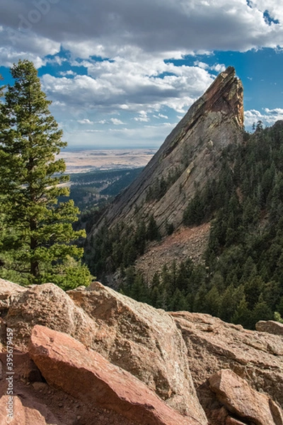 Fototapeta Flatiron in Boulder, Colorado. This view shows the rock face coming above the horizon with a blue sky with clouds and a city in the background