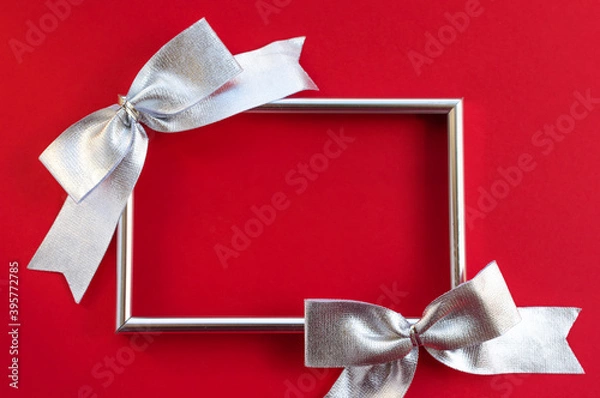 Obraz Bright festive background. empty frame and silver bows on a red background. conceptual greetings for Christmas, Thanksgiving, New Year, Mother's Day, Birthday, Valentine's Day. Flat lay, copy space