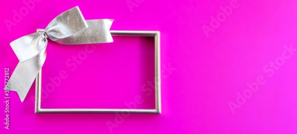 Obraz Silver empty frame with a bow on a fuchsia background. Banner. Greeting card for New Year, Christmas, Thanksgiving, mother's Day, Birthday. A place for a creative concept.