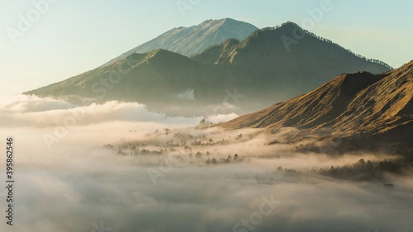 Fototapeta Sunrise view of mount Batur, Abang and Agung volcano in Bali from Pinggan village. Beautiful sunrise and low clouds. Layered minimalist landscape.
