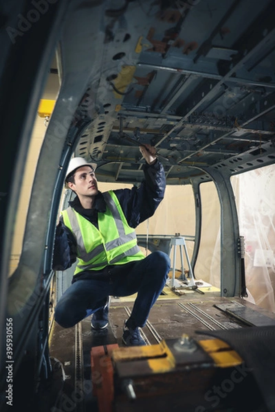 Fototapeta Portrait of a Caucasian man , factory engineer in work clothes controlling the work process at the helicopter manufacturer. 