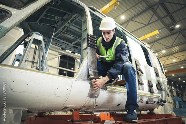 Fototapeta Portrait of a Caucasian man , factory engineer in work clothes controlling the work process at the helicopter manufacturer. 