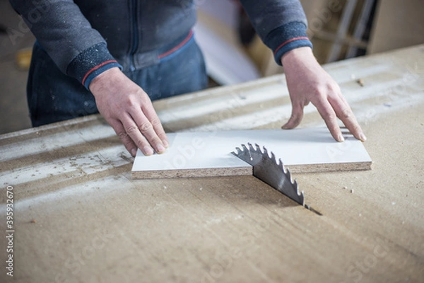 Fototapeta Close-up of a wooden cutting table with an electric circular saw. Professional carpenter cutting a wooden board at a sawmill. Sawing machine