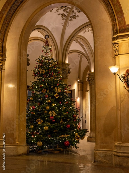 Obraz Elegantly decorated and perfectly shaped Christmas tree in an old gothic Building.  the gold colours of the ornaments fit perfectly with the hue of the old stone walls.