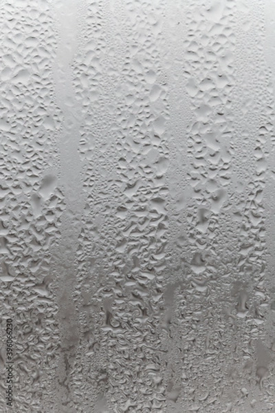 Fototapeta Natural drops of water flow down the glass, high humidity in the room, condensation on the glass window. Neutral colors. Vertical photo orientation