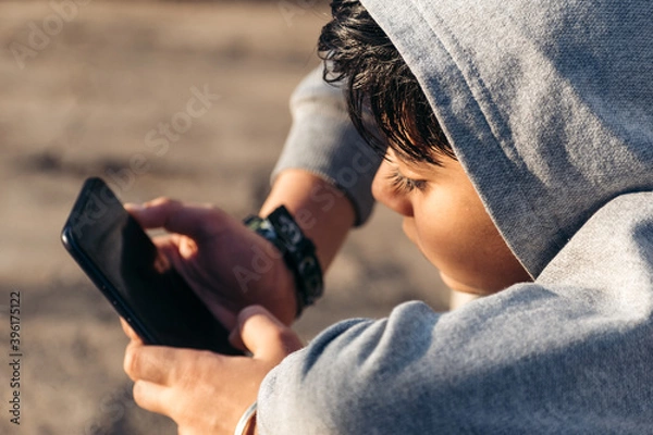 Obraz Portrait of little Indian boy using mobile phone indoor. Concept of mobile phone, technology addiction in young children