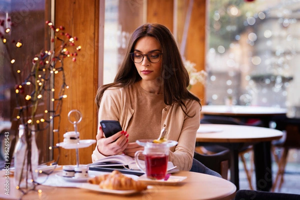 Fototapeta Beautiful woman text messaging while sitting in the cafe