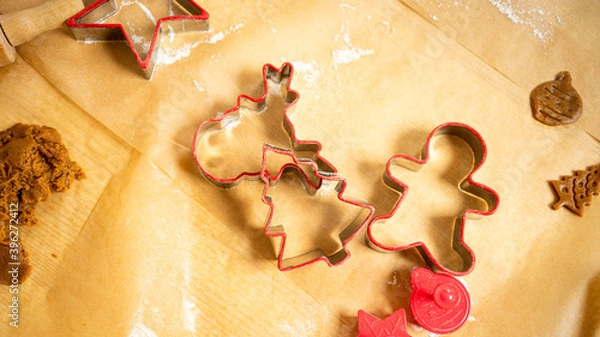Obraz Red ginger bread shapes and dough laying on brown baking paper. Baking gingerbread.