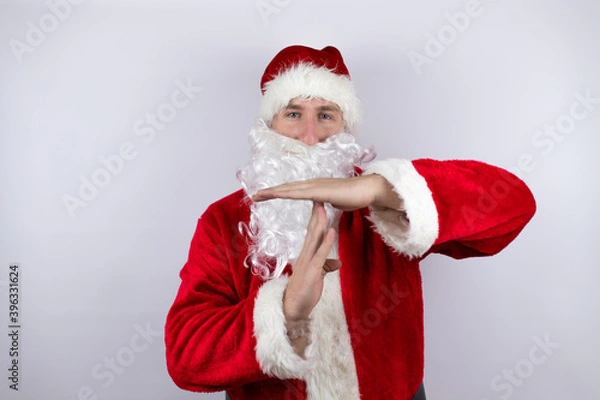 Obraz Man dressed as Santa Claus standing over isolated white background Doing time out gesture with hands, frustrated and serious face