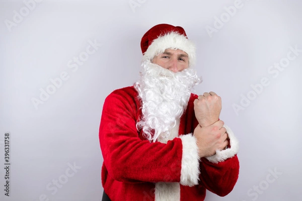 Fototapeta Man dressed as Santa Claus standing over isolated white background suffering pain on hands and fingers