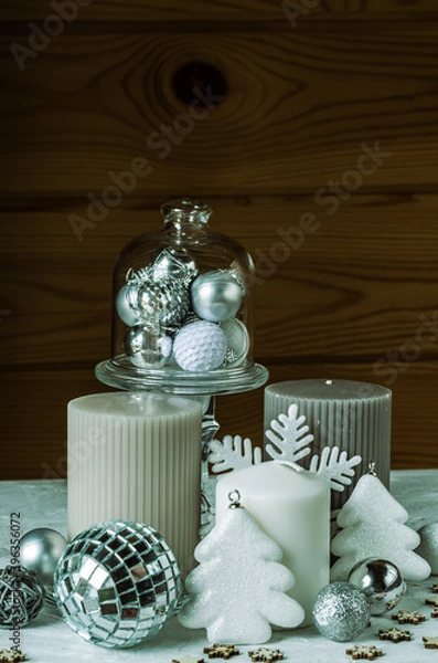 Fototapeta Christmas composition with candles, artificial trees, snowflakes and shiny white and gray Christmas balls on a wood background.