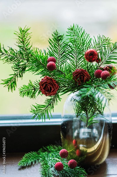 Fototapeta christmas composition with fir branches, artificial flowers and berries in a vase close-up.