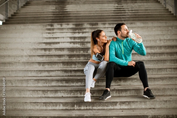 Fototapeta Young couple resting during training with bottle of water