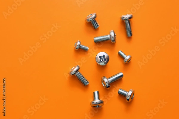 Obraz Metal drywall screws on a yellow background, top view, cross screw cap