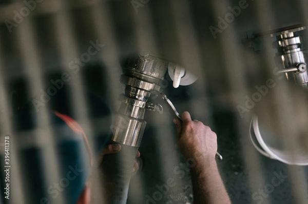 Obraz Man tightening a valve with a wrench