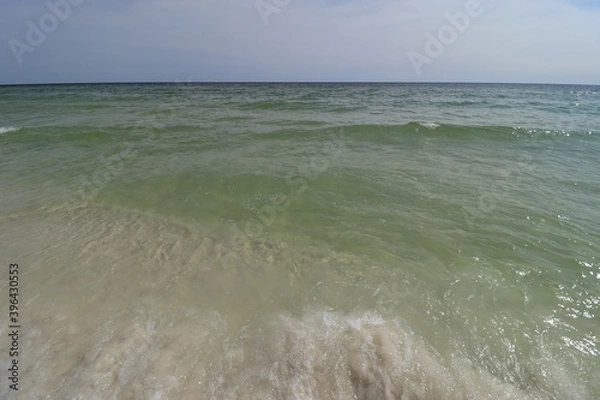 Fototapeta Close-up green wave on the ocean shore, small wave creates foam, shooting from the beach