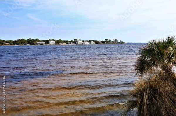Fototapeta A beautiful view of the mainland from opposite coast of the Gulf of Mexico, from Santa Rose Island, the blue waters of the ocean gleam with the brownish-yellow color of the clay bottom