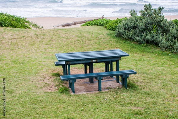 Fototapeta Green Picnic Table on a Grassly Slope Overlooking the Sea