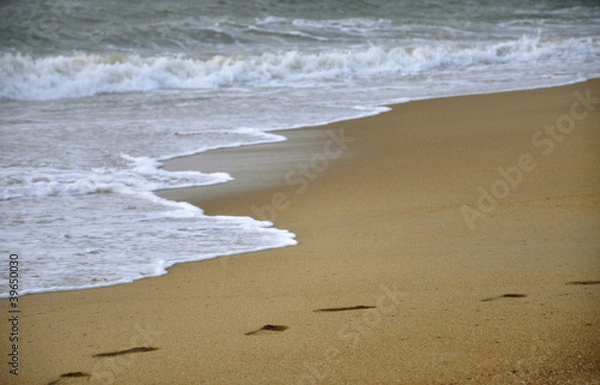 Fototapeta Footprints left behind in the sand at the beach
