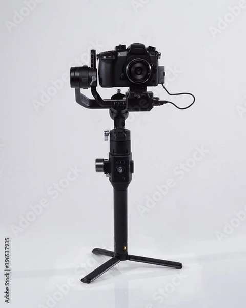 Fototapeta Mirrorles professional cameras with a gimbal camera stabilizer. Video Camera Gimbal Stabilization Tripod System on a white background. Gimbals Stabilization System with Mirrorless Camera.