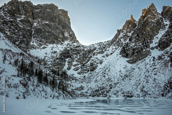 Fototapeta View of Emerald Lake in Rocky Mountain National Park in Colorado during the winter. The lake is frozen over and the mountain range is covered in snow.