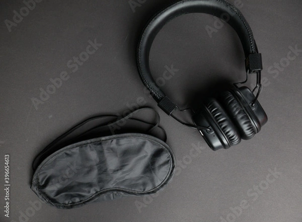 Obraz Classic black wired headphones on black paper background with sleeping mask. Retro style. 80s. Pop culture. Top view. Minimal Music Concept