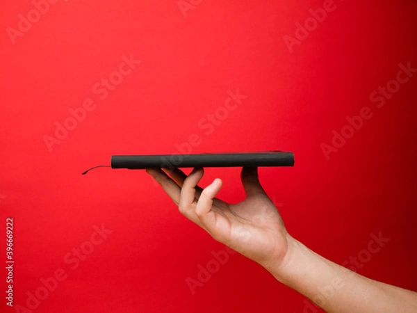 Fototapeta Hand of European men holding black note. Isolated on red background. Studio portrait.