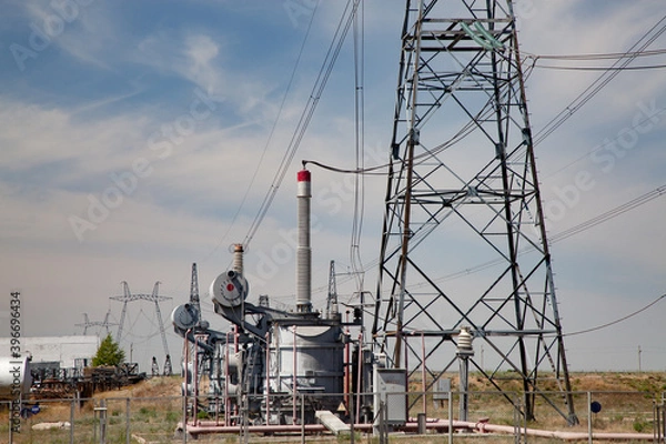 Fototapeta Electric transformer with isolators and pylons. Distributing substation Kegos. Blue sky with light clouds background.
