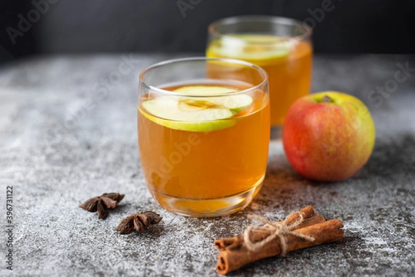 Fototapeta Hot apple cider or punch on gray concrete background. Traditional Christmas or New Year warming spicy beverage with cinnamon, star anise. Non-alcoholic drink recipe idea for cold weather.