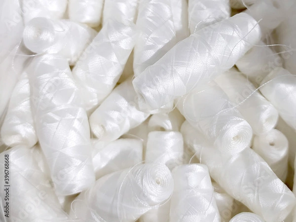 Fototapeta Lots of white polyester and silk threads. Sewing machine spools. Background on the theme of light industry