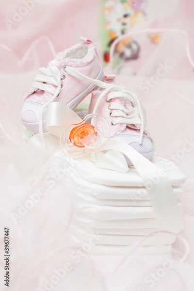 Obraz Baby shoes and orange pacifier on cotton diapers