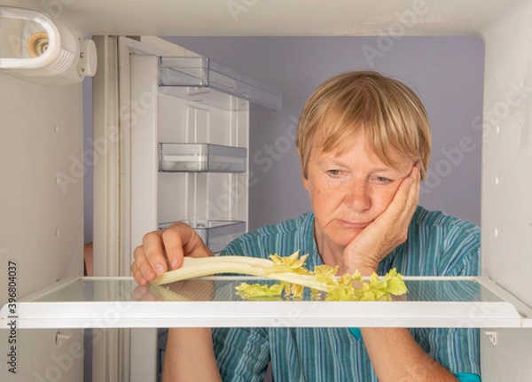 Fototapeta Senior woman looking inside an empty fridge 