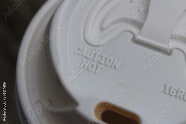 Fototapeta A plastic to go coffee lid with a warning label that reads 'caution hot'.