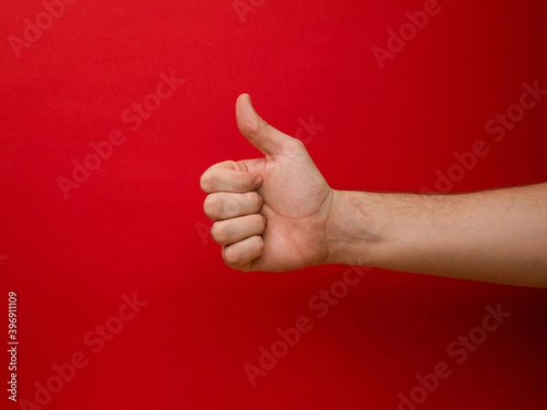 Fototapeta Female hand shows thumb up gesture on a red background