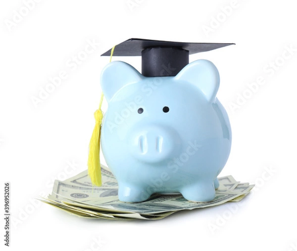 Fototapeta Piggy bank with graduation hat and money on white background. Tuition fees concept