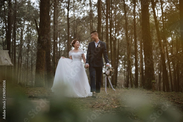 Obraz The newlyweds happy in the atmosphere of the pine forest, looking and feeling warm.